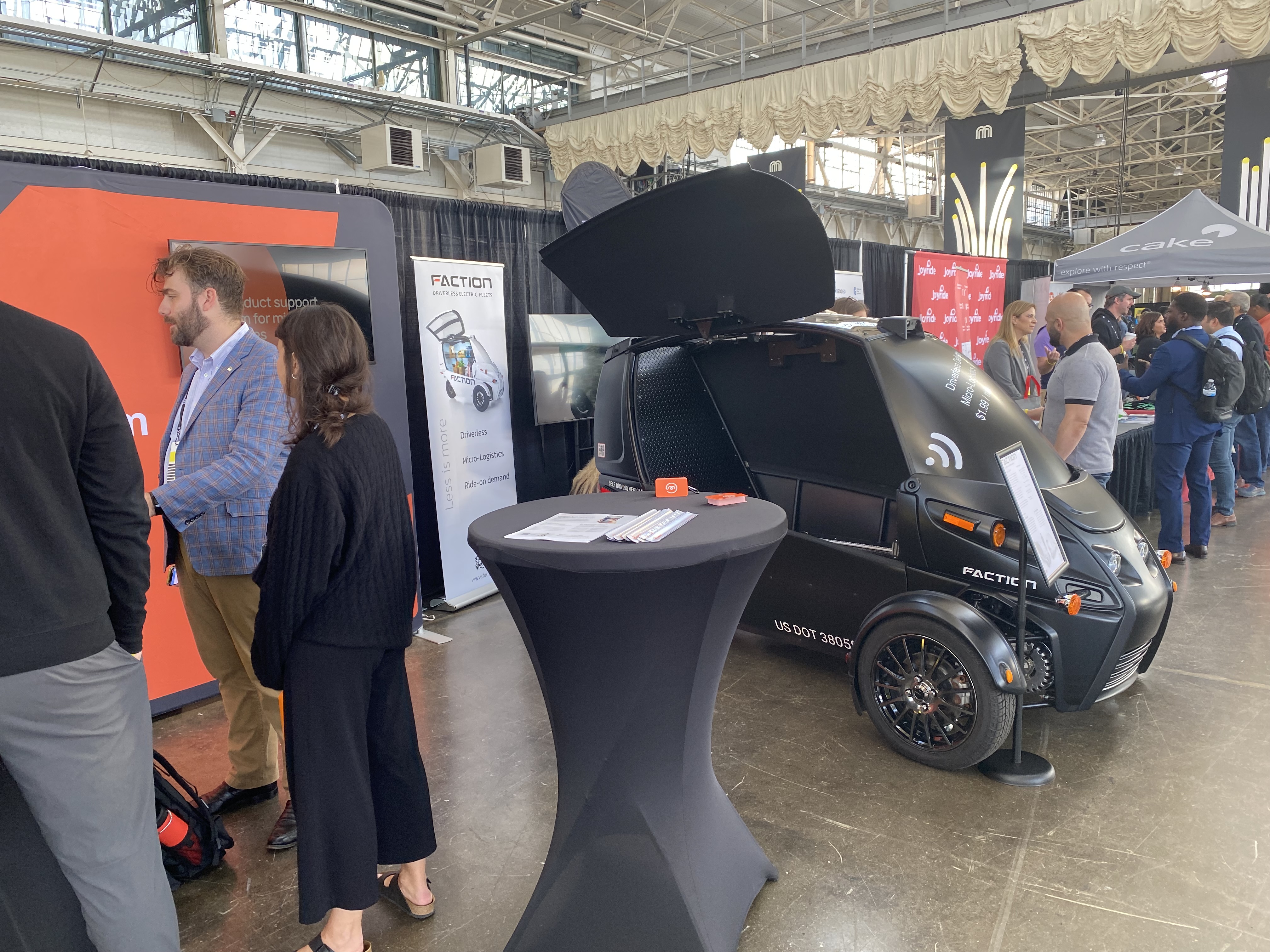 Trade show floor showing small, electric car from manufacturer Faction
